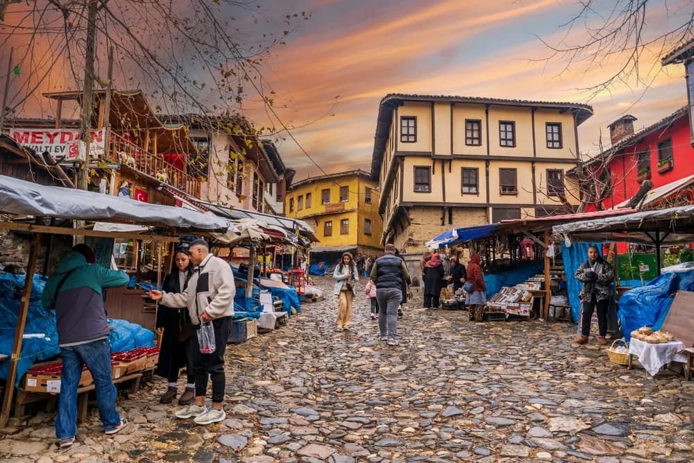 A cobblestone old town street lined with traditional wooden houses and market stalls