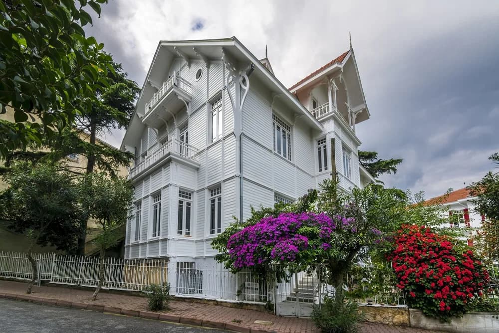 A restored white wooden Ottoman-era mansion with a flowering garden, Istanbul