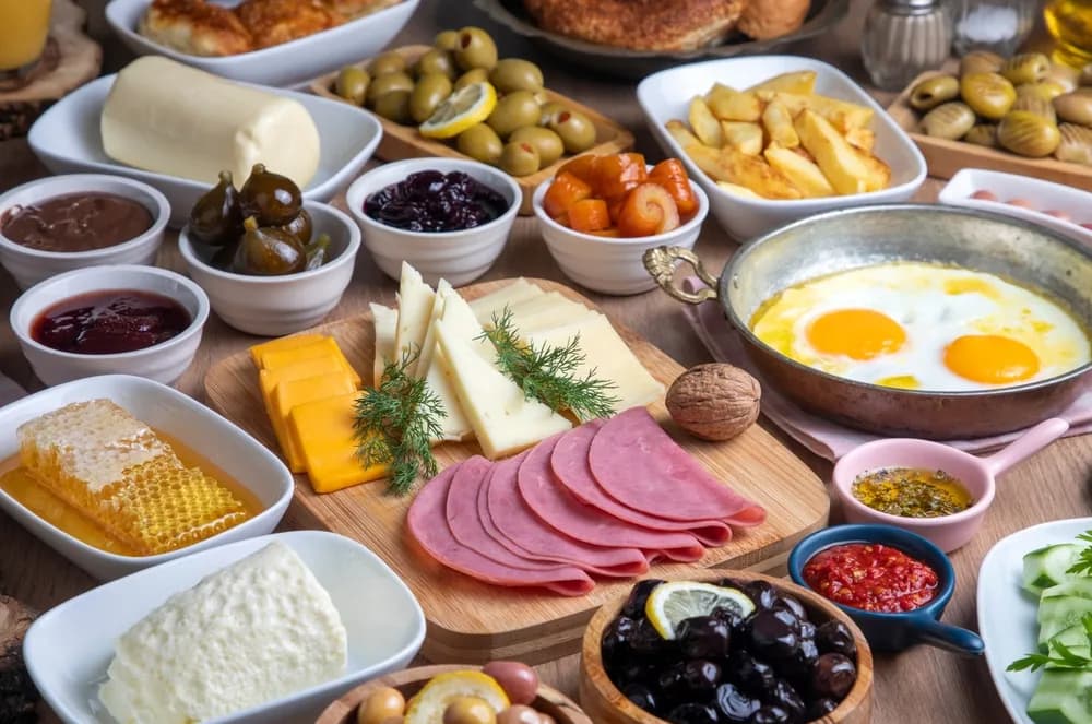 A spread of Turkish breakfast dishes including cheeses, olives, honeycomb, and eggs