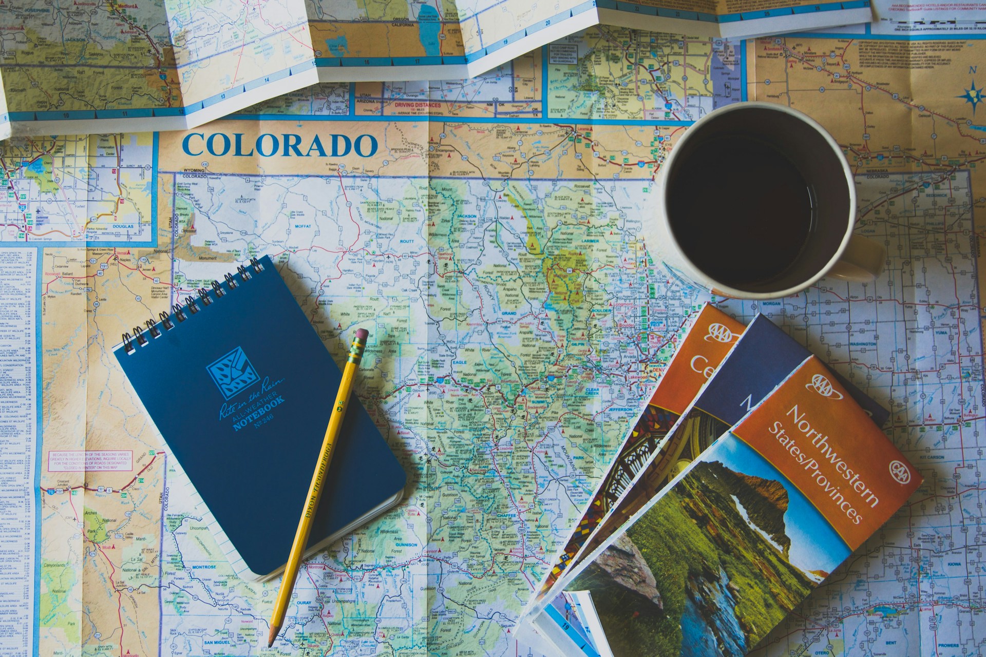 a map with a pencil and a notebook and a coffee cup